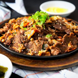 Delicious Korean BBQ beef dish with vegetables and sesame sprinkled on a hot plate.
