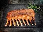 Delicious grilled spare ribs served with fresh herbs on a stone surface.