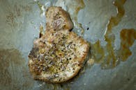 A deliciously seasoned and cooked pork chop resting on a baking tray, ready to serve.