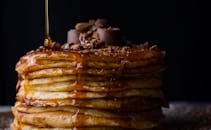 Mouthwatering stack of pancakes topped with chocolate and syrup. Perfect breakfast delight.